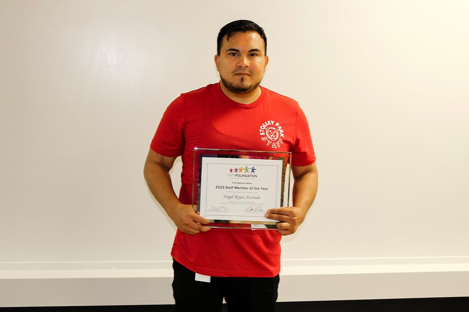 Angel Rojas Acevedo standing with his Staff Member of the Year plaque